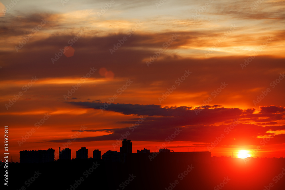 Sunrise in city landscape. Urban sunset. Rays of the sun above t