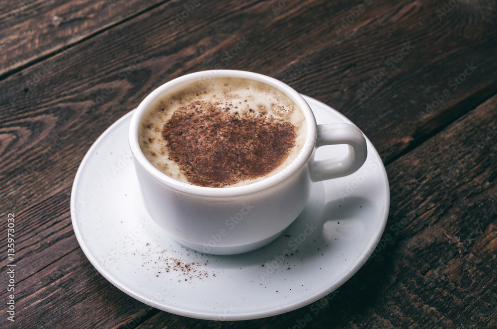 White coffee cup with heart shape on dark wooden background White coffee cup with heart shape on dark wooden background