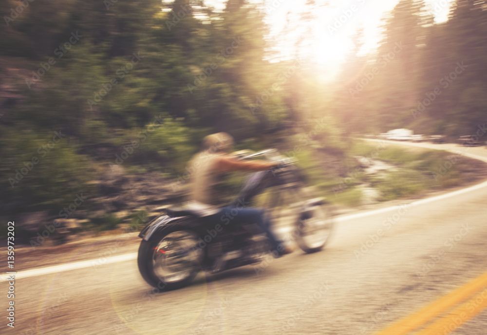 biker on mountain highway, riding around a curve with a motion blur toned with a retro vintage instagram filter app or action