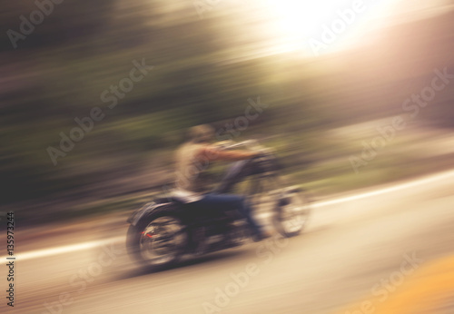 biker on mountain highway, riding around a curve with a motion b