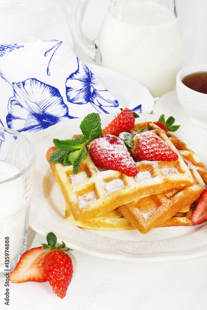 Hot homemade belgian waffles with berries and milk on light back Hot homemade belgian waffles with berries and milk on light back