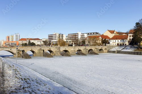 Winter oldest stone Bridge in central Europe above frozen River Otava, Pisek, Czech Republic