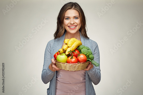 Smiling young woman holding fruit set.