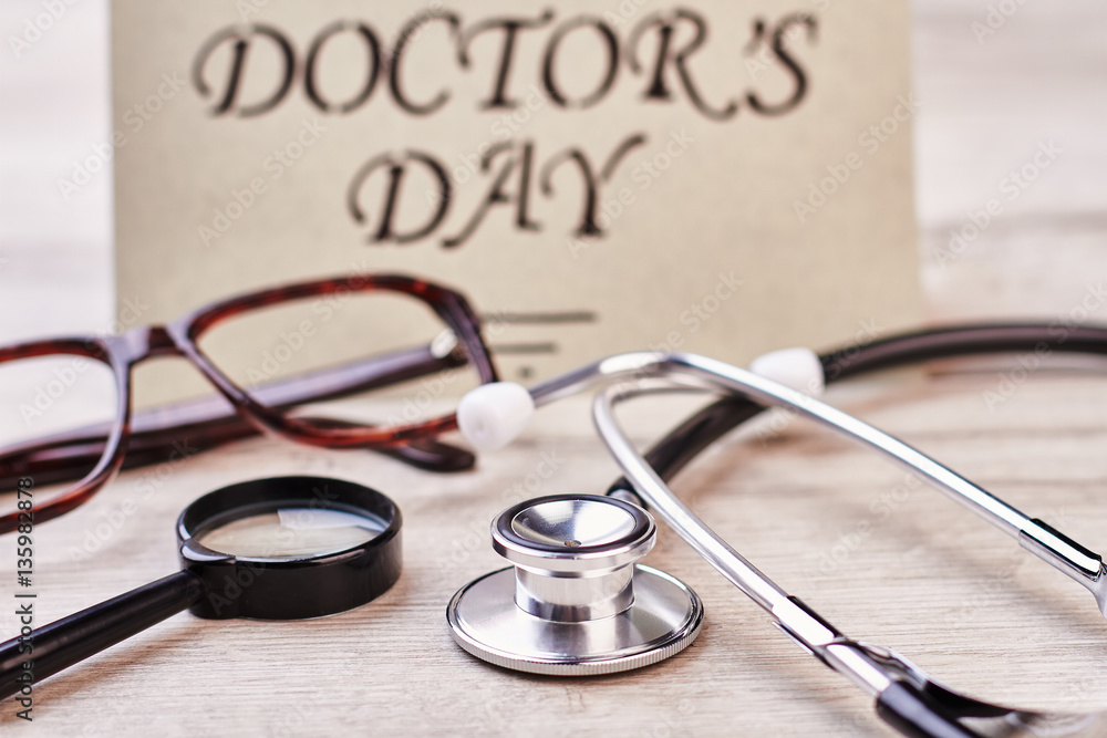 Loupe, stethoscope and greeting card. Spectacles on wooden surface. Loupe, stethoscope and greeting card. Spectacles on wooden surface.