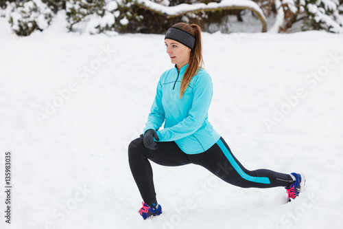 Winter workout. Girl wearing sportswear, stretching exercises.