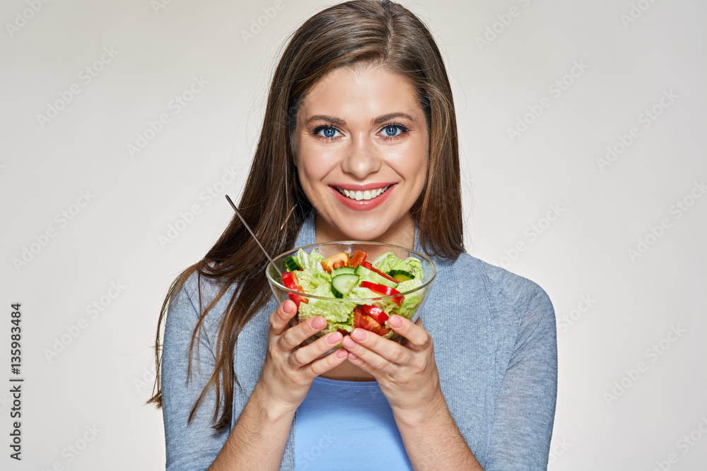 Smiling woman holding glass bowl with green salad.