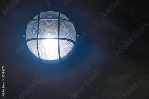 Tungsten wall lamp glowing over dark background.