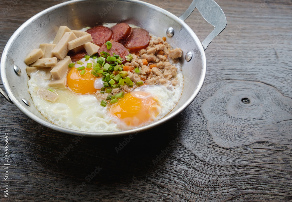 Side view closeup pan fried eggs with spinach breakfast menu in a pan with wooden background, healthy concept.