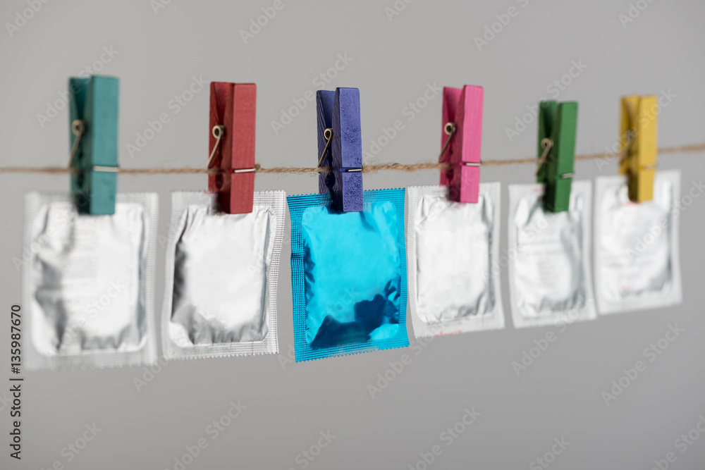 Condoms hanging on the rope on gray background.