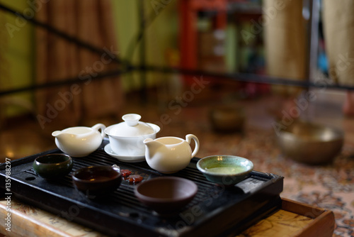 Chinese ceramic cup with green tea on wooden tray. Traditional tea ceremony. Soft focus