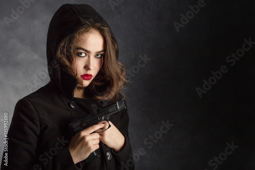 serious girl with gun on black background