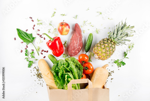 Paper bag full of healthy food on a white background photo
