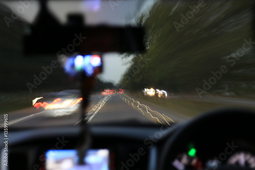 Night road view from inside car natural light street and other cars is motion blurred, Blur image from inside a car traveling at night time.