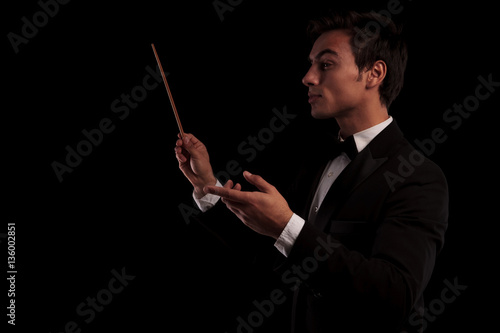 side view of an elegant music conductor holding a batton photo