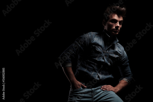 dramatic young man sitting on chair with hand in pocket