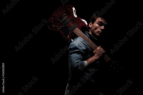 side view of a guitarist holding his guitar on shoulder
