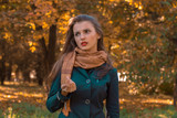 young girl in Brown silk scarf stands in the Park and looks away