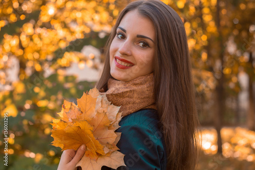 beautiful girl with red lips turned her head smiling and holding a leaf