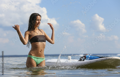 Young beautiful girl is sprinkling water of the sea near surf de
