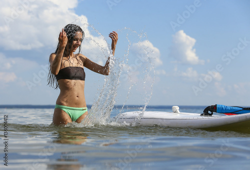 Young beautiful woman is sprinkling water of the sea near surf d