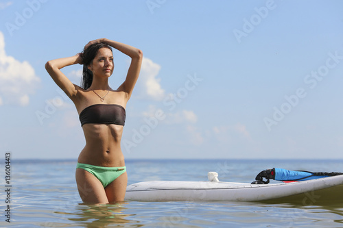 Young beautiful woman is standing near the surf desk in the ocea