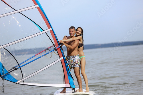Young man and woman are standing on the surfing desk in the sea