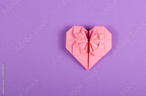 Pink Valentine origami on a lilac background. Heart of paper. Surprise on Valentine's Day. Copy spaсe.