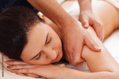 Masseur massaging female shoulders closeup. Portrait of young woman enjoying relaxing massage. Beauty, relax, rest, health care, body, pleasure, stress relief concept