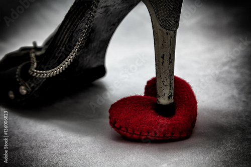 women shoes stomp on broken heart in dark tone., unrequited love., love concept for valentines day.