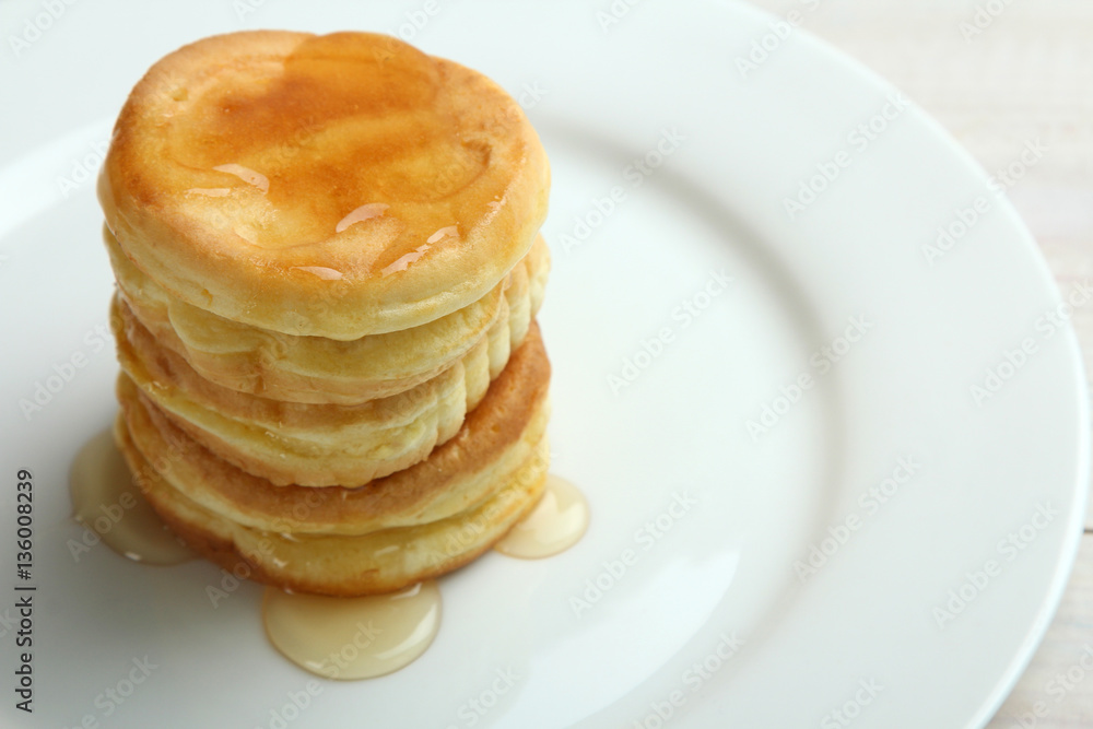 Stack of pancakes with honey on a plate.