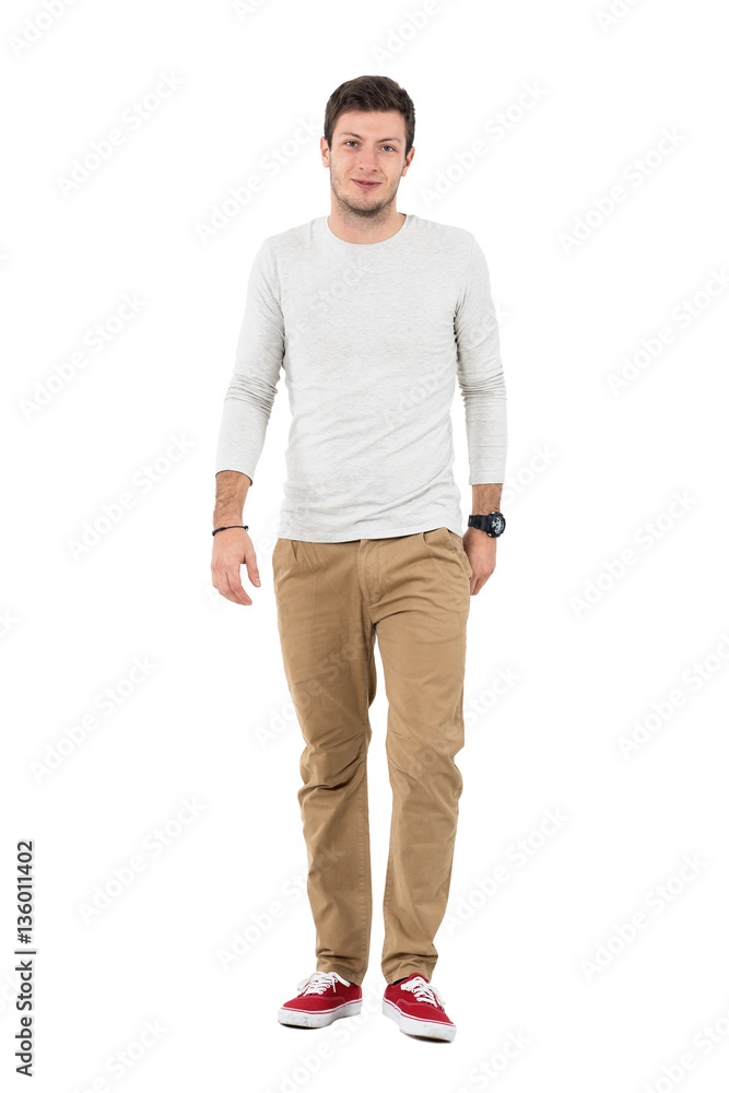 Friendly smiling man in beige pants walking towards camera. Full body length portrait isolated over white studio background. Friendly smiling man in beige pants walking towards camera. Full body length portrait isolated over white studio background.