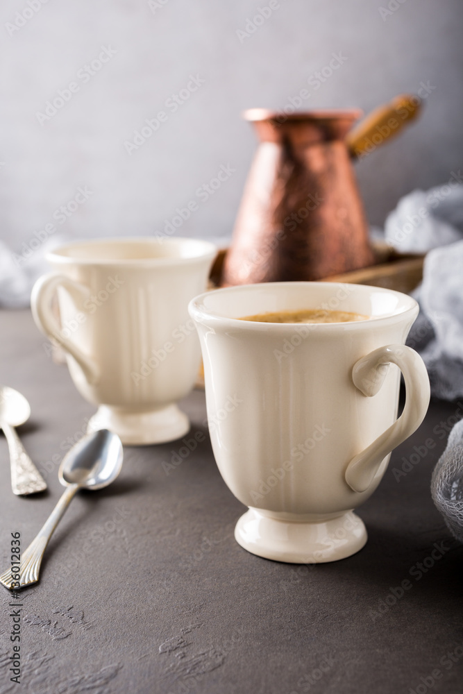 Two retro cups of coffee and old coffee pot on dark brown background with copy space. Two retro cups of coffee and old coffee pot on dark brown background with copy space.