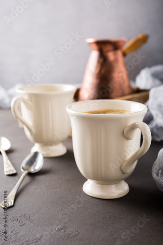 Two retro cups of coffee and old coffee pot on dark brown background with copy space.