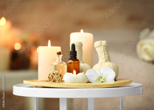 Bottles of essential oil, herbal bags and candles on wooden tray