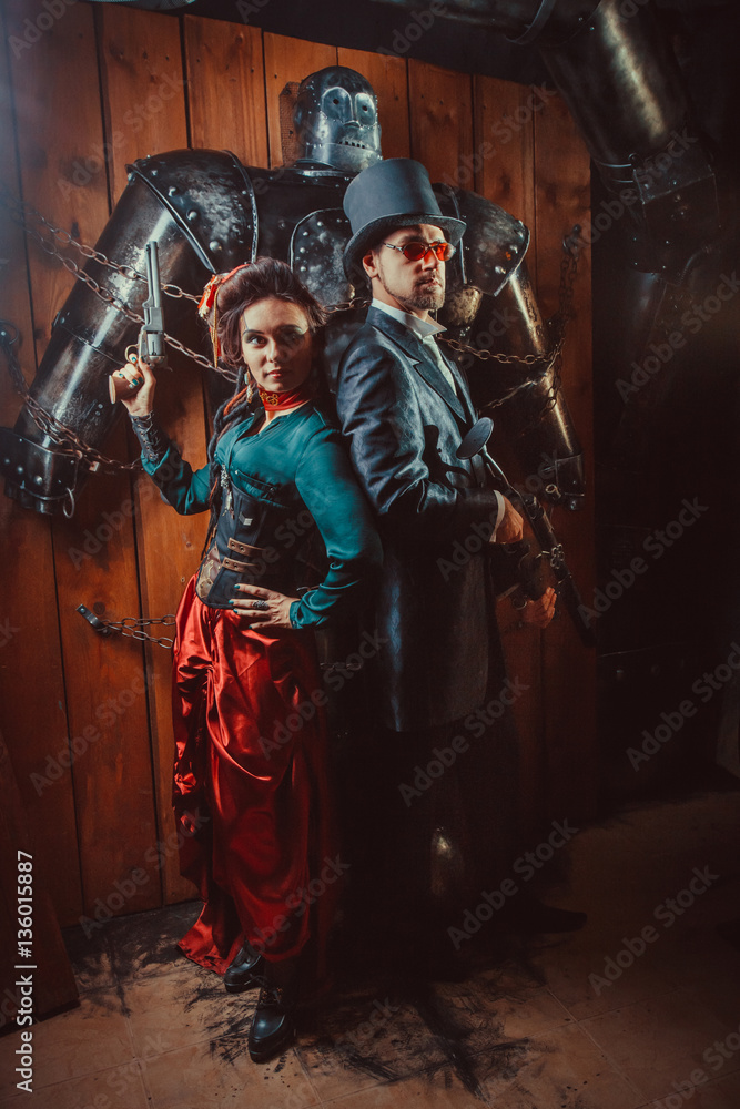 Beautiful couple with the guns and big tied robot on the background.