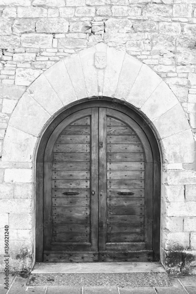 The entrance wooden door in an old Italian house (black and white).