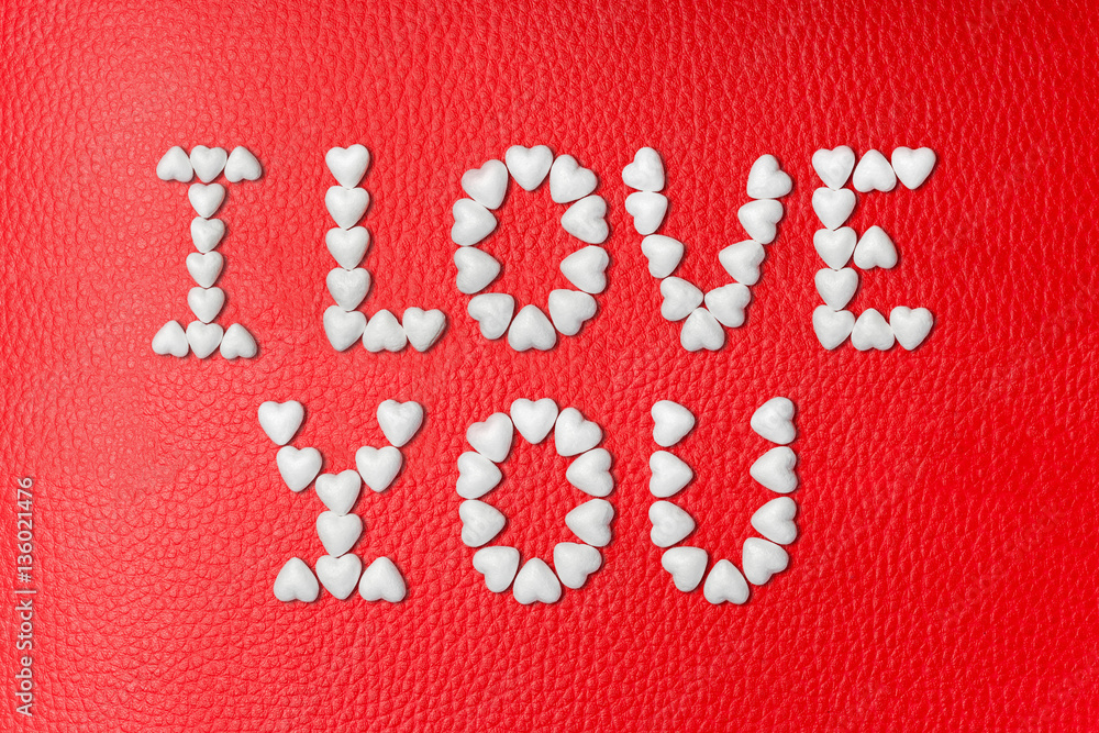 The inscription I LOVE YOU made from white hearts on red leather background