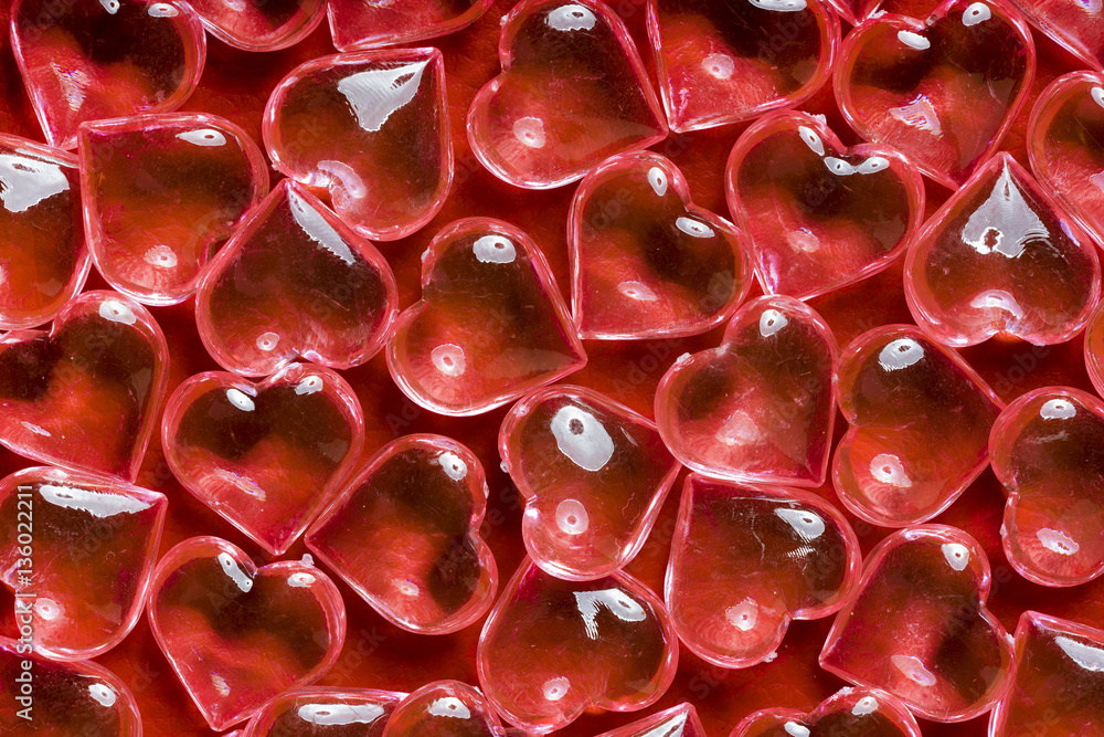 Transparent glass hearts on a red leather background Transparent glass hearts on a red leather background