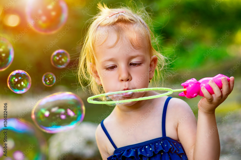 Cute little girl with blowing soap bubbles in park Cute little girl with blowing soap bubbles in park