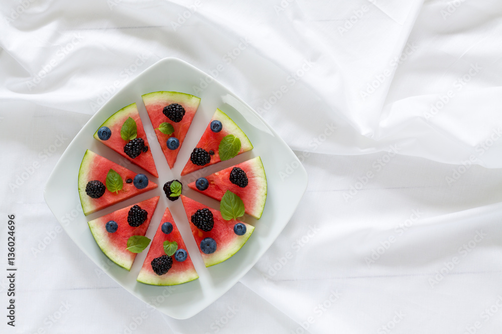 Pieces of ripe watermelon looks like a pizza on plate on the table. Horizontal view from above.