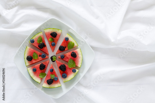 Obraz na płótnie Pieces of ripe watermelon looks like a pizza on plate on the table. Horizontal view from above. w salonie