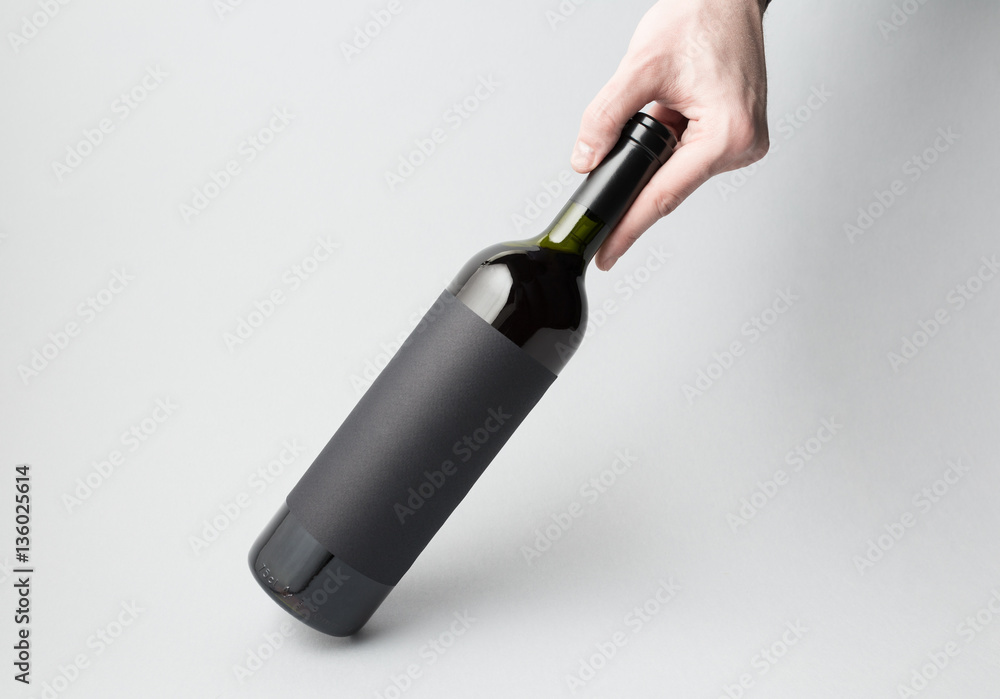 Hand is holding wine bottle on gray background Hand is holding wine bottle on gray background