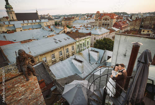Romantic moment of the newlyweds on the roof on the sunset © myronovychoksana