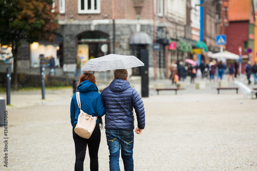 Couple with umbrella in the rain goes on the street of European city