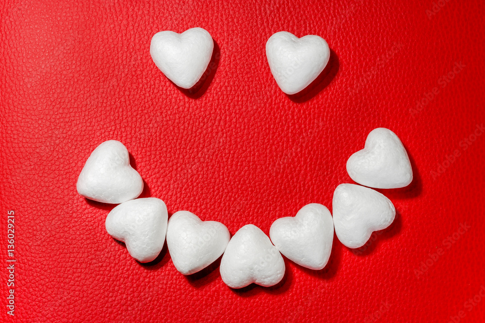 Obraz premium Happy face made from white hearts on red leather background