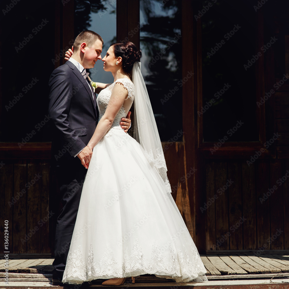 Bride and groom look in each other eyes while they stand on the wooden porch Bride and groom look in each other eyes while they stand on the wooden porch