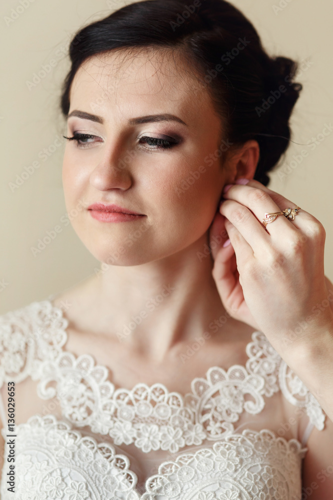 Bridesmaid puts earrings on bride's ear