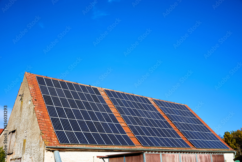 Altes Scheunendach mit Solarkollektoren vor blauem Himmel