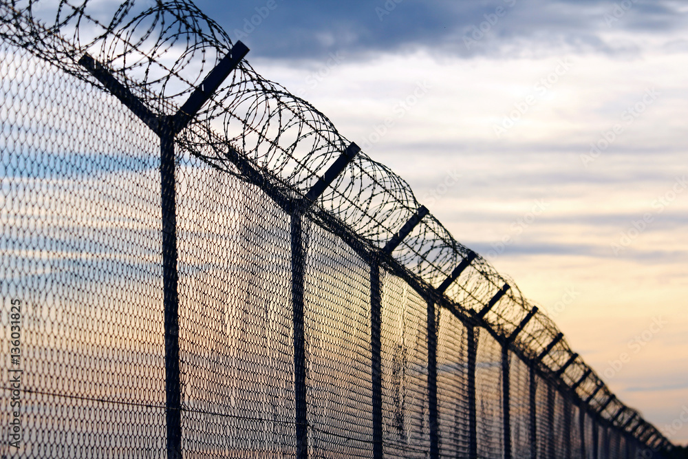 Silhouette of Barbed Wire fence against a Cloudy Sky Silhouette of Barbed Wire fence against a Cloudy Sky