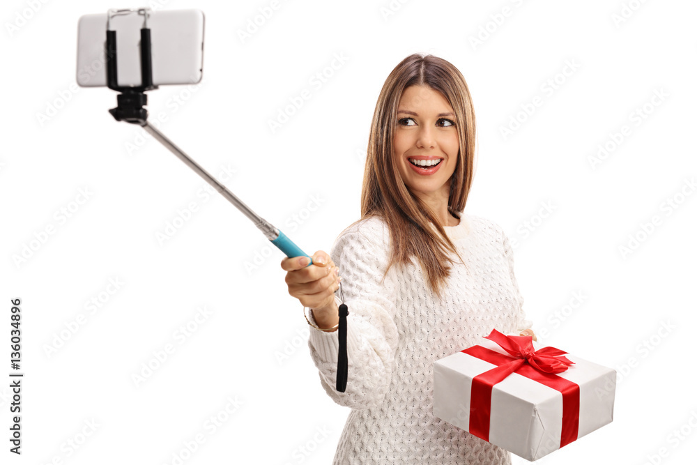 Happy woman holding present and taking selfie with a stick Happy woman holding present and taking selfie with a stick